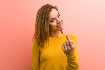 Young pretty young woman pointing with finger at you as if inviting come closer.