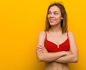 Young caucasian woman wearing bikini and sunglasses smiling confident with crossed arms.