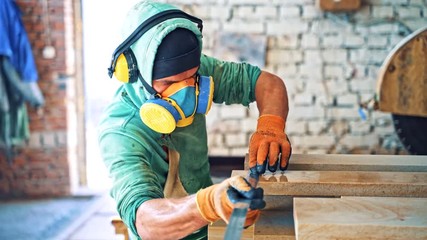 Man in protective uniform measures the stone slabs in factory. cutted stone slabs on the industrial plant background. Worker with the ruler in manufacture.