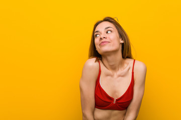 Obraz premium Young caucasian woman wearing bikini and sunglasses dreaming of achieving goals and purposes