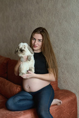 Young pregnant woman. Pregnant beautiful woman with rabbit posing at home. Happy pregnancy. Woman expecting baby. Maternity. Healthy pregnancy concept, parenthood.