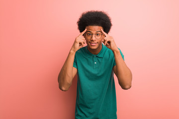 Young african american man over a pink wall doing a concentration gesture