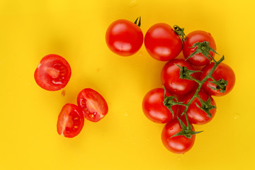 Naklejka na ściany i meble Ripe fresh Juicy organic cherry tomatoes on branch and cut tomato on yellow plastic cutting board. Top view. Horizontal.