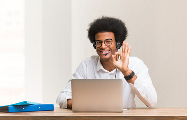 Young telemarketer black man cheerful and confident doing ok gesture