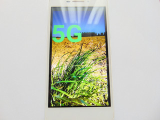 Mobile with displayed 5 g. Bright sun on the screen future concept.
