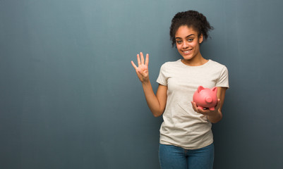 Young black woman showing number four. She is holding a piggy bank.