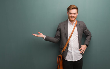 Young redhead business man holding something with hand