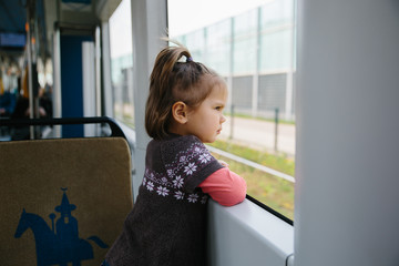 Baby girl commuting by tram at window seat