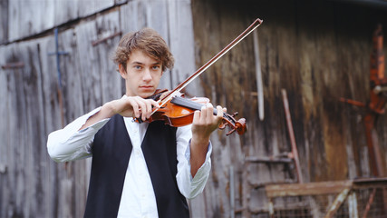 Young violin player in front of retro wooden building