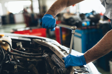 closeup worker holding wrench in car service
