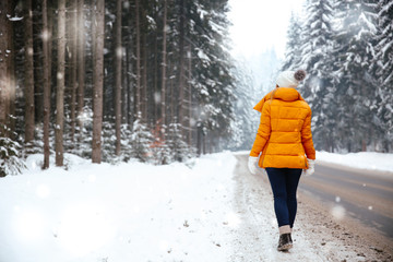 Beautiful young woman near road in winter forest