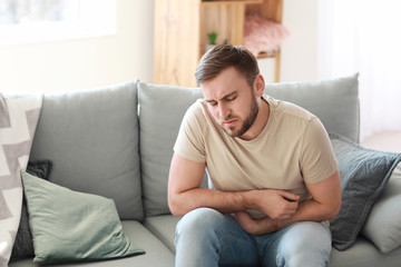 Young man suffering from stomachache at home