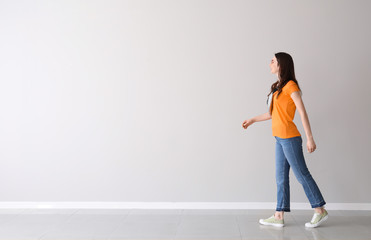 Going young woman near light wall