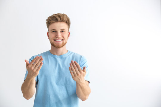 Handsome young man inviting viewer against light background