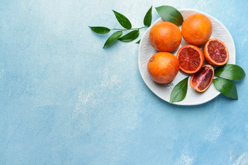 Plate with fresh blood oranges on color background