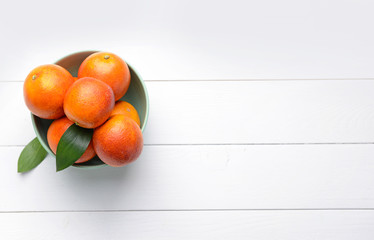 Bowl with fresh blood oranges on white wooden table