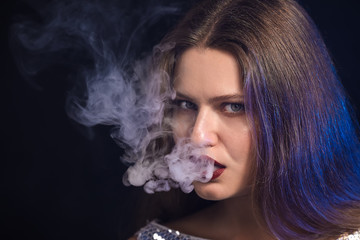 Young woman smoking on dark background