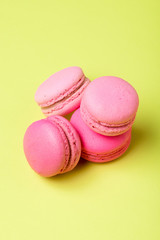 tasty pink macarons with filling on yellow surface
