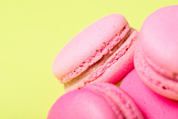 tasty pink macarons with filling on yellow surface