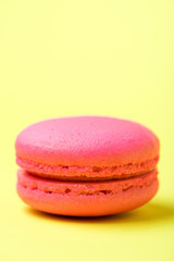 pink macaron cookie with filling on yellow surface
