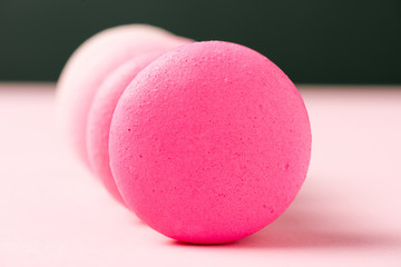 selective focus of sweet colorful macarons on pink surface