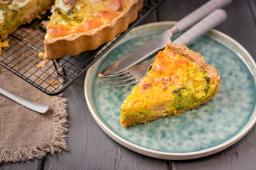 Traditional broccoli pie with salmon and cheese. Food from healthy and healthy foods. Lunch. A piece of cake in the frame on a plate. Dark photo.