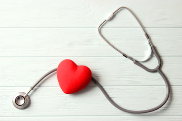 Stethoscope and heart on wooden color background. Health, medicine