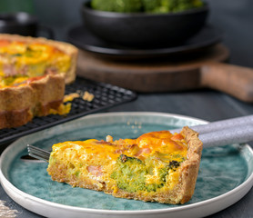 Traditional broccoli pie with salmon and cheese. Food from healthy and healthy foods. Lunch. A piece of cake in the frame on a plate. Dark photo.