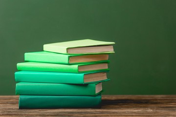 stack of colorful books on wooden surface isolated on green