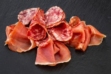 Italian prosciutto crudo or spanish jamon and sausages. Raw ham on stone cutting board