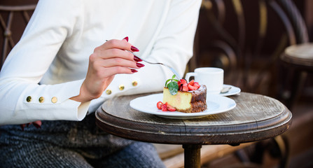 Obraz na płótnie Canvas Piece of cake with red berry. Gourmet recipe food. Cake slice on white plate. Cake with cream delicious dessert. Appetite concept. Dessert cake cup of coffee and female hand with fork close up