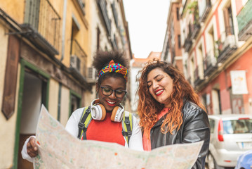 Two Latin Teenage Girls Using a Map and Traveling Together.