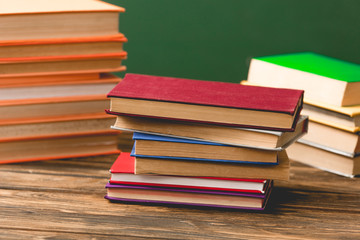 colorful hardcover books on wooden surface isolated on green