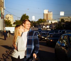 happy couple is embracing in the street, near the roadway. stand near the fence next to the carriageway