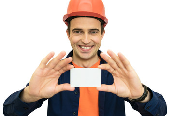 Handsome young guy with protective helmet on his head person shows a business card, isolated, background with a copy of the space