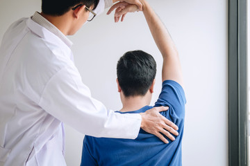 Doctor physiotherapist assisting a male patient while giving exercising treatment massaging the...