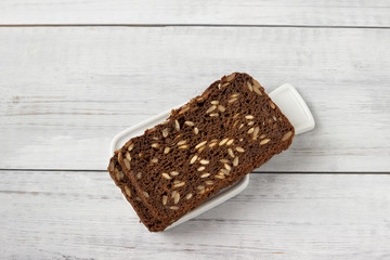 Two slices wholemeal rye bread with different seeds on white table.