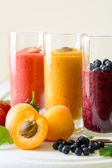 Strawberry, blueberry and apricot smoothies on white wooden background. Detox and healthy eating concept