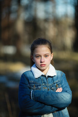 Portrait of a schoolgirl in a denim jacket in the park.