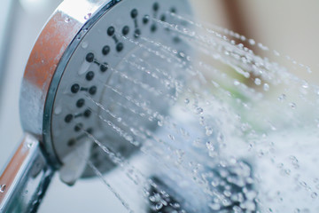 Naklejka na ściany i meble Image of a modern shower head splashing water close up background
