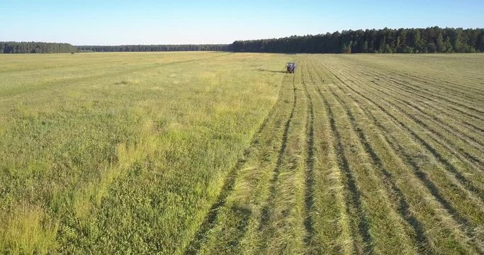close motion above field haymaker mower moves along boundless farmland and gathers grass against pictorial landscape