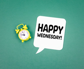 Happy Wednesday. Paper speech bubble and Alarm Clock on a Green Background