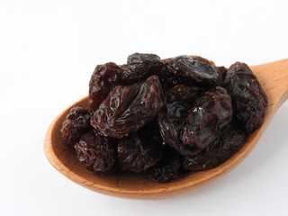High angle view of raisins on wooden spoon isolated on white background. A raisin is a dried grape Dry food. It tastes sweet and delicious. Texture detail of raisin surface. Food concept.