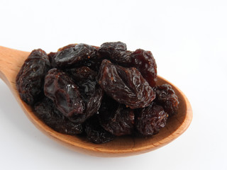 High angle view of raisins on wooden spoon isolated on white background. A raisin is a dried grape Dry food. It tastes sweet and delicious. Texture detail of raisin surface. Food concept.