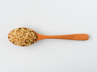 Top view of raw brown rice (also called hulled rice, unpolished rice,husked rice) on wooden spoon isolated on white background. Rich nutrition. Asian food,Health, agriculture concept. With copy space.