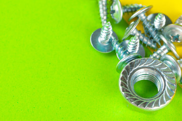 Top view of stainless steel bolts or iron nails on bright green background