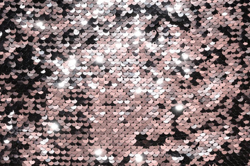 Sequin fabric background. Close-up shot of glittery black sequins texture reflecting red light