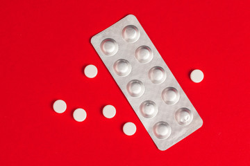 Pills in blisters on red background top view. Medicine