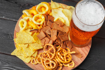 Lager beer and snacks on wooden table. Nuts, chips, pretzel