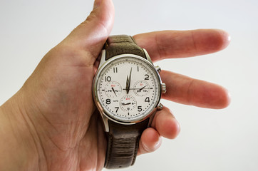 men's, wristwatches with brown strap in hand, isolated on white background. Close-up.
